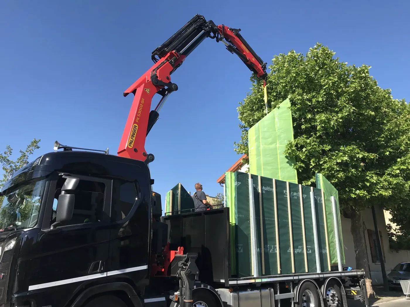 Camion-grue Palfinger DUSOGAT livrant des panneaux ossature bois sur chantier